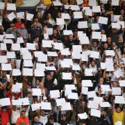Wanderers fans hold up white cards during the second leg of the play-offs in what was a packed out Toughsheet Stadium