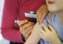 A child about to be given the MMR (mumps, measles, rubella) vaccination into their arm by a surgery nurse with a hypodermic syringe, England, UK..