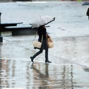A shopper walks across Victoria Square in the rain