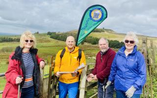 Rotarians Pat Rothwell, Christopher Hill, Graham and Susan Stamford installing new waymarker roundels on a stretch of the Rotary Way Bolton with Rivington Pike in the background