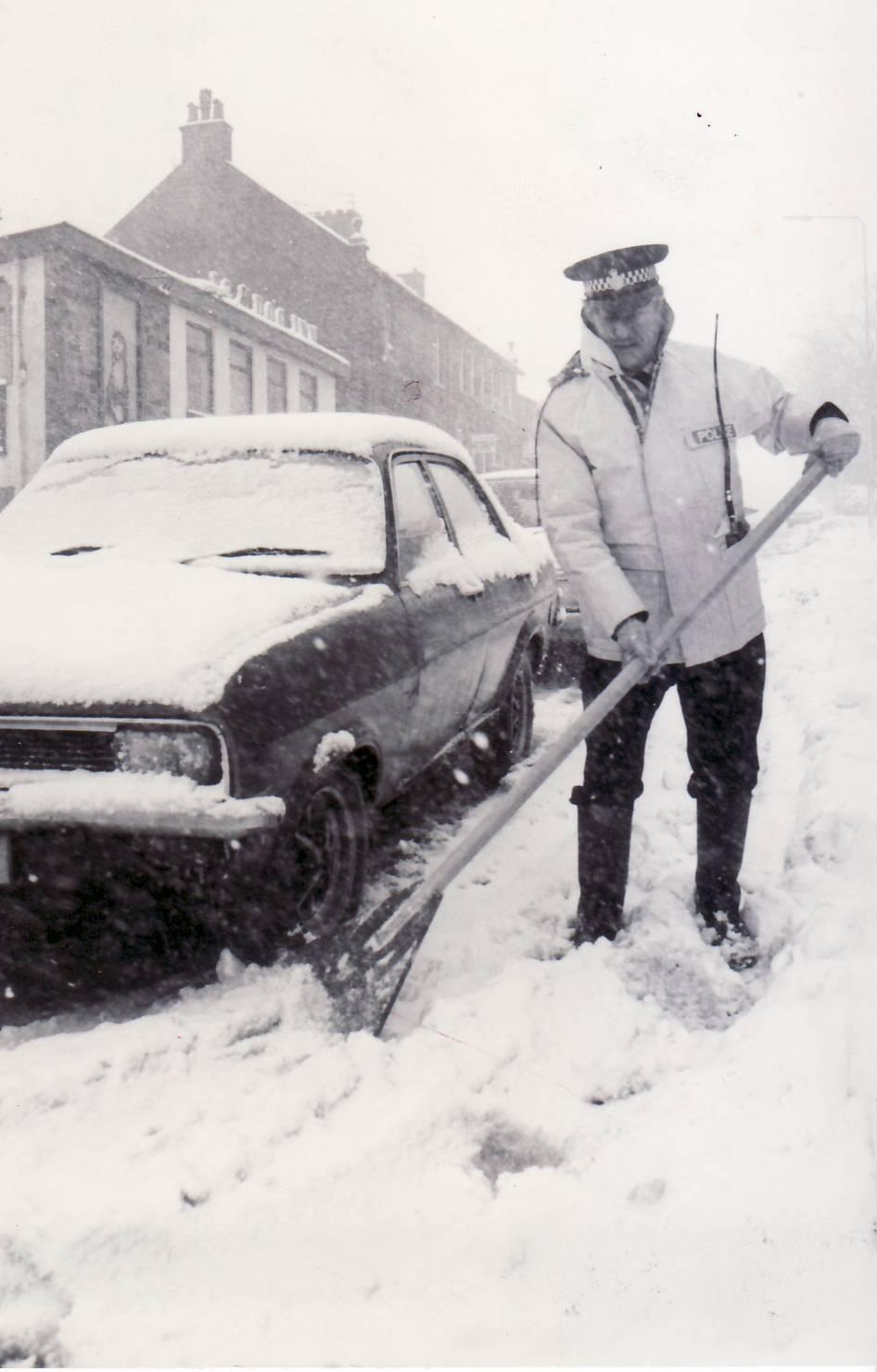 January 1984 - Belmont policeman Bill Gilbertson clears away snow for a driver
