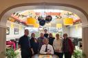 Tasos (middle) with staff and customers celebrating 35 years with a cake
