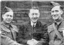 A Canadian handshake between Pte. Dave Smith, Mr. Fred Entwisle and Pte. Tommy Noon