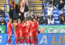 Wigan's players celebrate a goal in front of the Bolton Wanderers supporters at the UniBol.