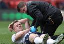 George Johnston is treated by physio Matt Barrass after hurting his ankle at Charlton
