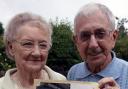Joan and Ralph O’Toole holding a picture of them standing in front of their old post office in Brownlow Fold