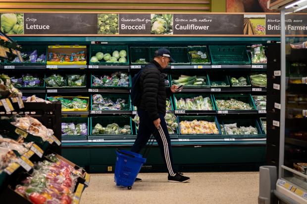 The Bolton News: A shopper walks through the salad aisle in a branch of Tesco (PA)