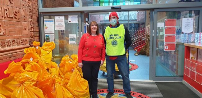 SHARING CHRISTMAS -  At Clarendon Primary School Deputy Headteacher Claire Caldwell receives bags of gifts from one of the Bolton Lions