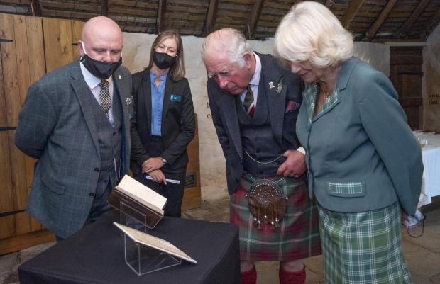 The Bolton News: The Prince of Wales and the Duchess of Cornwall, known as the Duke and Duchess of Rothesay when in Scotland, take a look at the original manuscript of Auld Lang Syne during a visit to Robert Burns' Cottage in Alloway, South Ayrshire. Photo via PA/Jane Barlow.