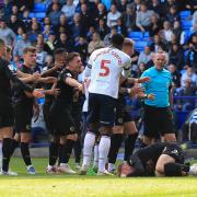 Referee Carl Brooks is surrounded by players after Bolton Wanderers' George Johnston fouls Peterborough United's Jack Taylor for which he was booked