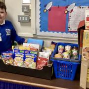 Henry Murphy with the supplies that teachers donated to achieve his basket of food and drink