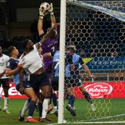 Wycombe Wanderers' Max Stryjek catches a corner under pressure from Bolton Wanderers' Ricardo Santos, whose shirt is being pulled by Chris Forino