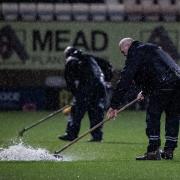Ground staff sweeping water off the pitch at Cambridge