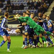 Wigan Athletic's Sam Tickle punches corner under pressure from Bolton Wanderers' Aaron Collins