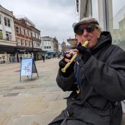 Brian plays his recorder to members of the public outside TSB