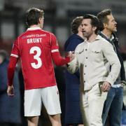 Wrexham co-owners Rob McElhenney and Ryan Renyolds with Lewis Brunt on the pitch