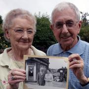 Joan and Ralph O’Toole holding a picture of them standing in front of their old post office in Brownlow Fold