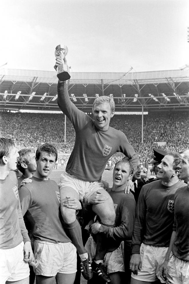 WINNER: England's triumphant 1966 World Cup final captain Bobby Moore chaired by hat-trick hero Geoff Hurst, left, and Ray Wilson as he holds aloft the Jules Rimet trophy